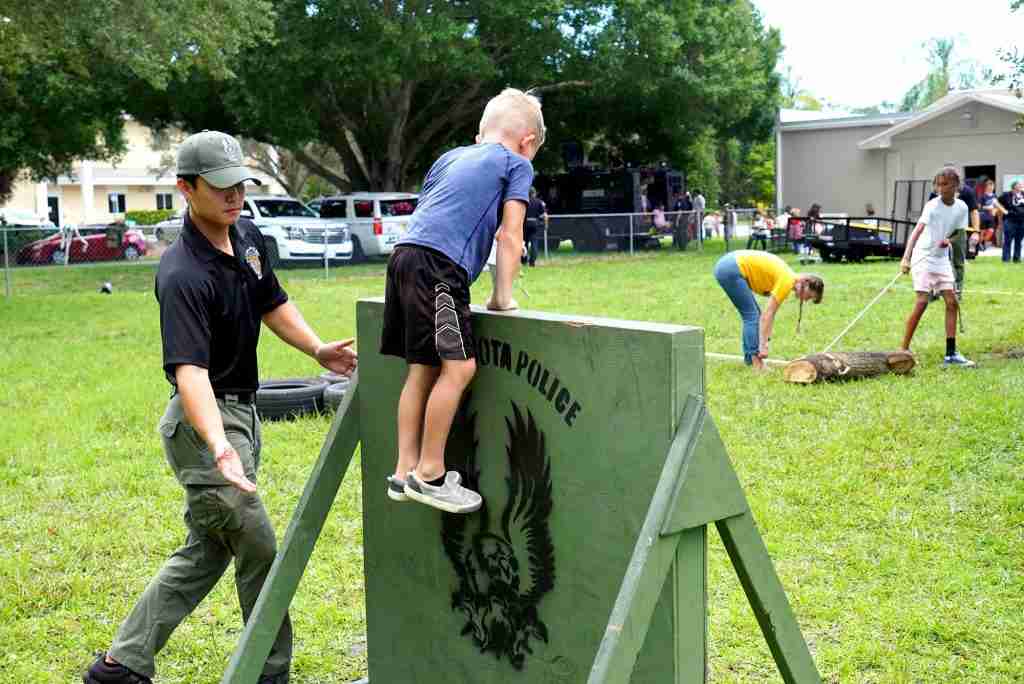 police officer helping child over training wall